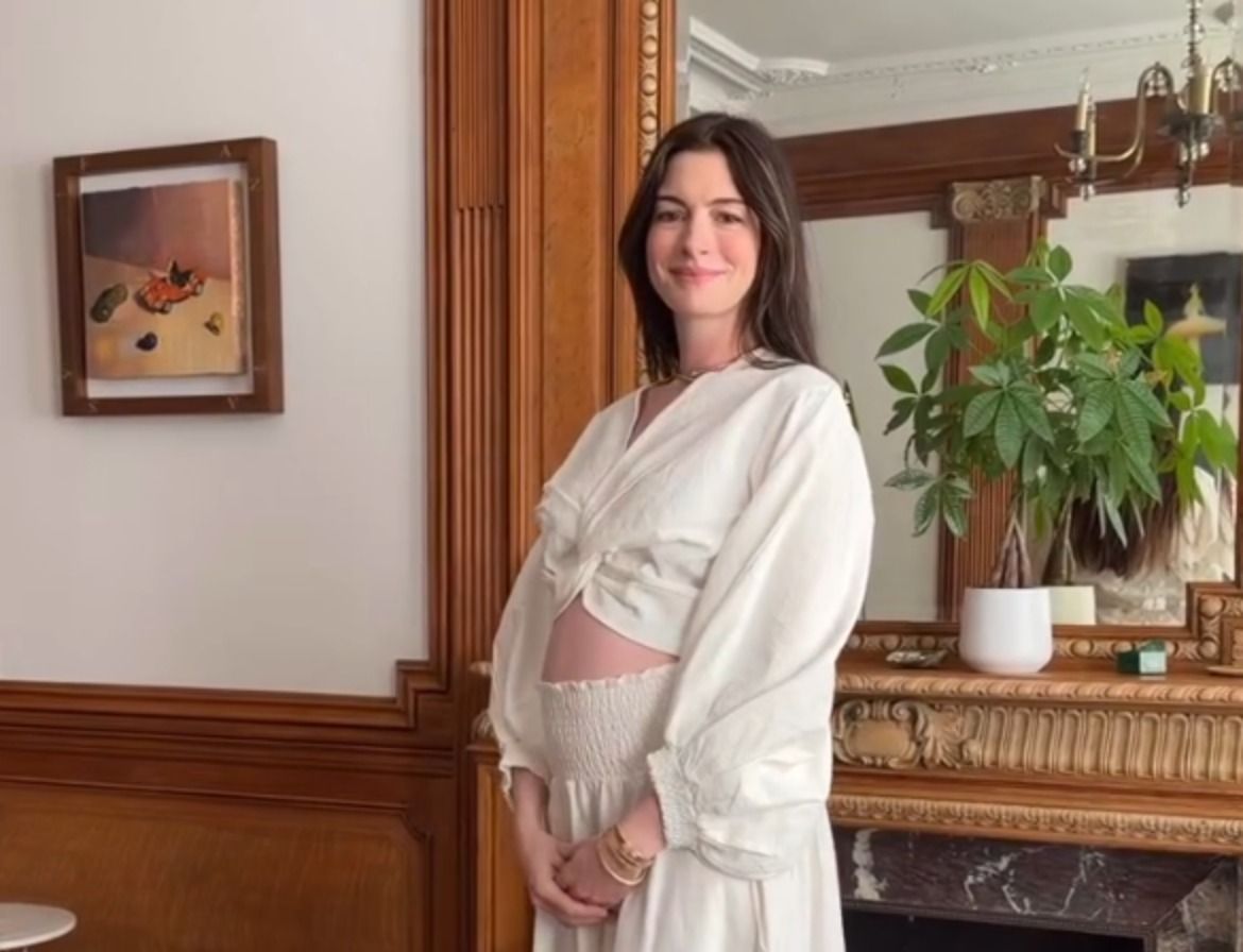 Anne Hathaway anuncia terceira gravidez abraçando a barriga com vestido branco